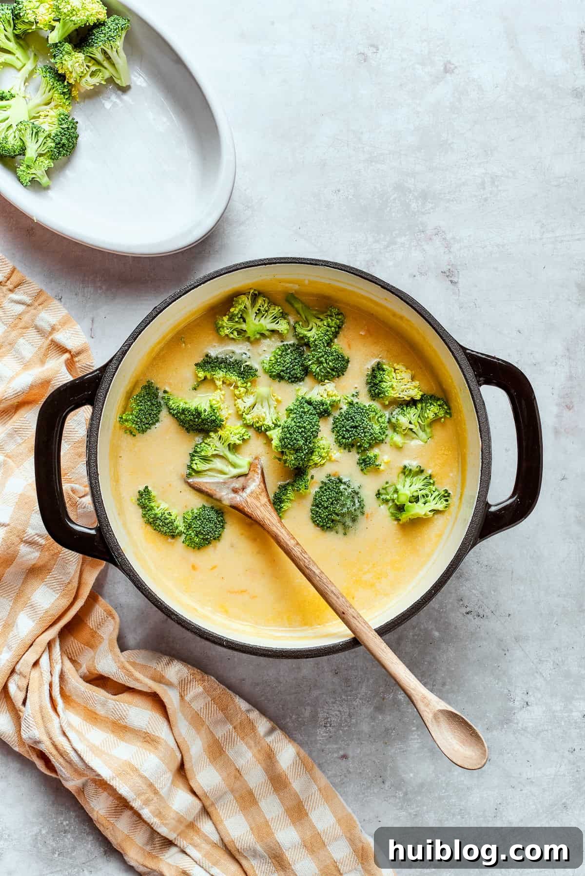 Stirring fresh broccoli florets into a pot of simmering soup, adding color and nutrients.