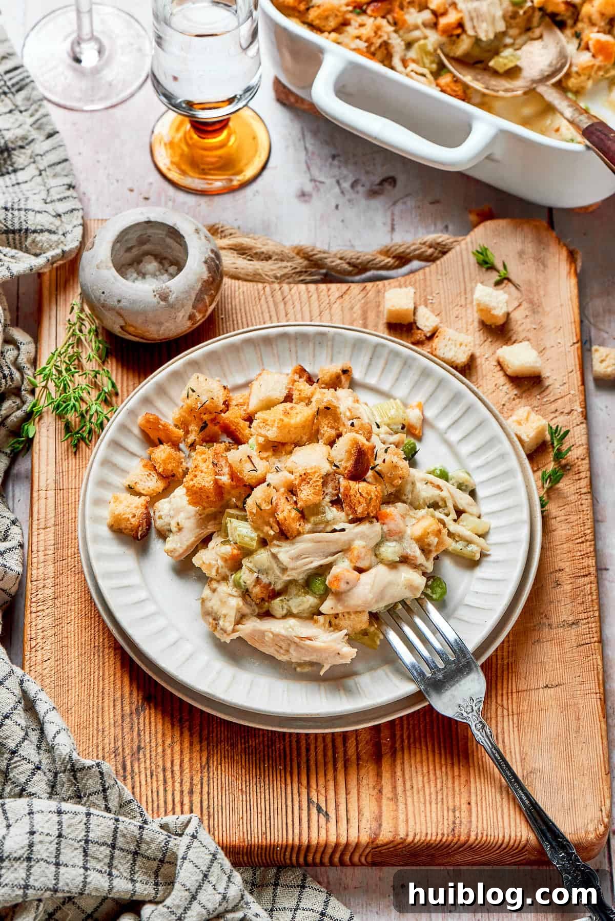 This chicken stuffing casserole features tender chicken filling with veggies topped with classic stuffing. An easy recipe baked until golden! A generous serving of chicken stuffing casserole on a white plate, garnished with fresh parsley.