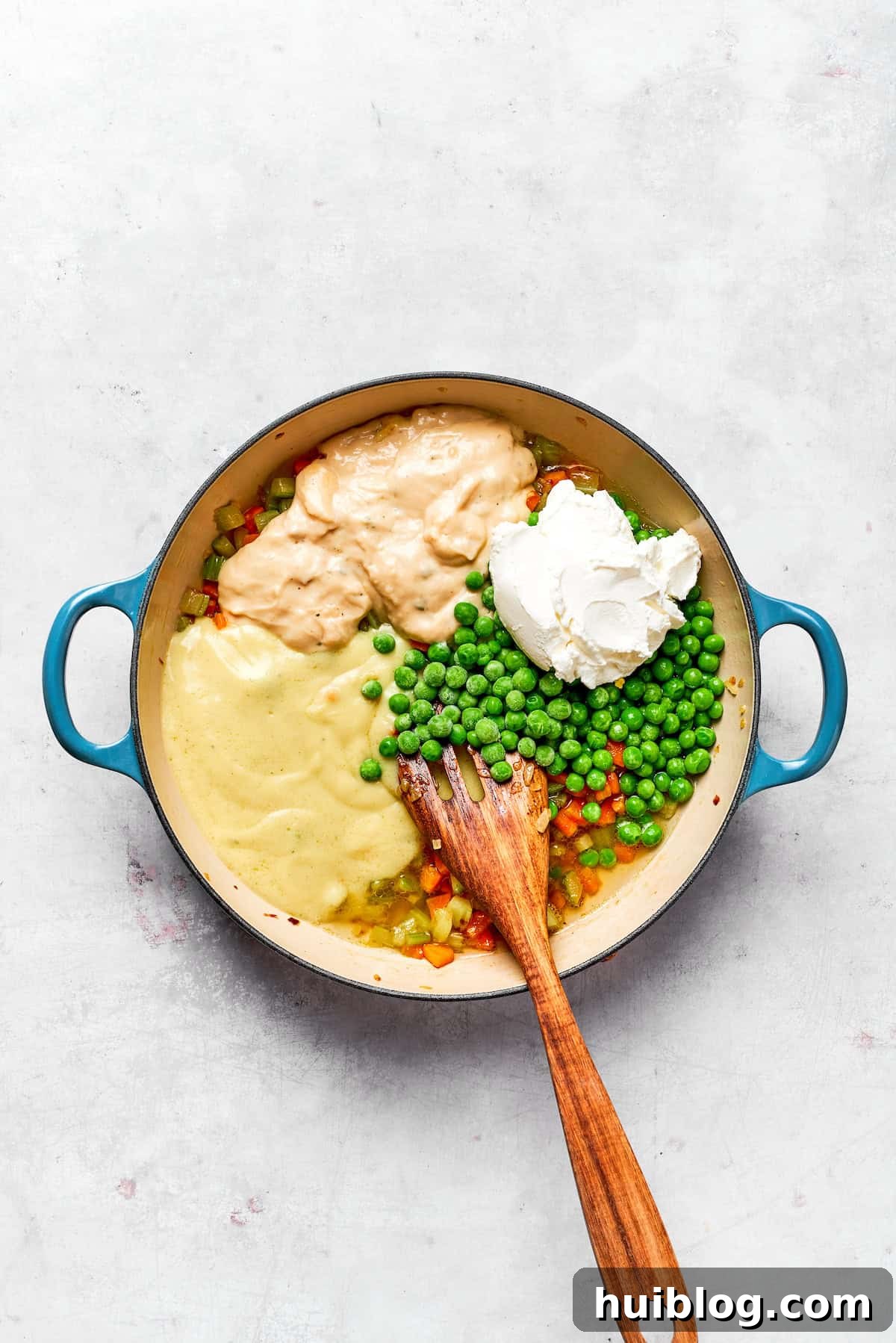 This chicken stuffing casserole features tender chicken filling with veggies topped with classic stuffing. An easy recipe baked until golden! Adding sour cream, condensed soups, and peas to the sautéed vegetables.
