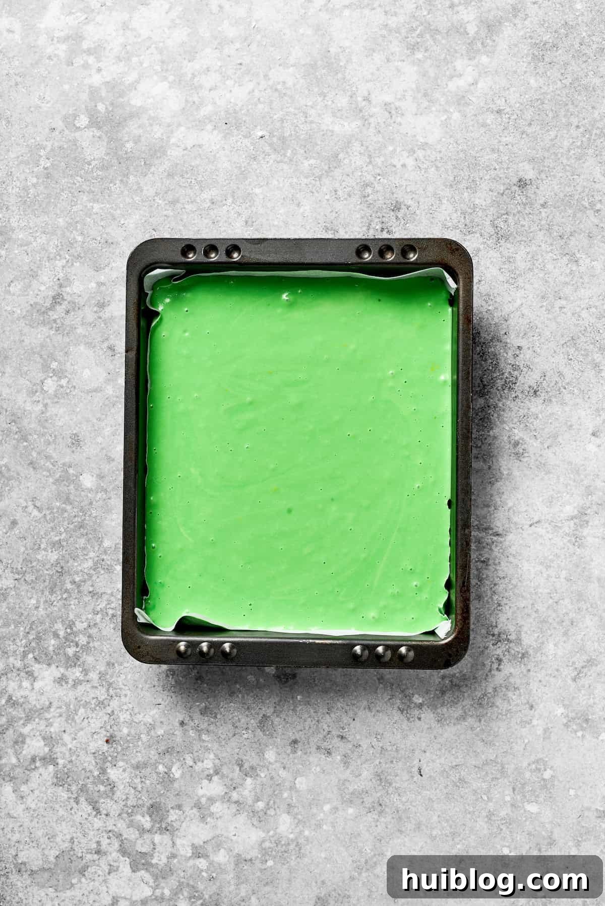 A square baking pan filled with bright green cake batter.
