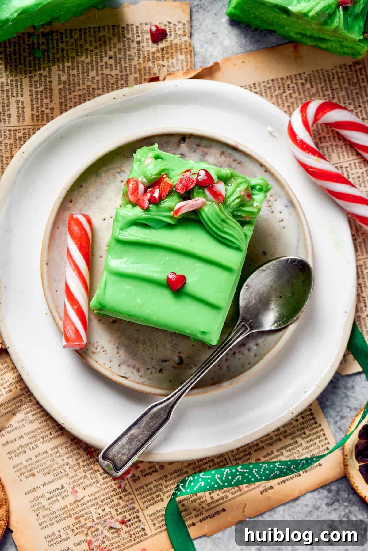 A plate with a single slice of green Grinch cake and a spoon, ready to be enjoyed.