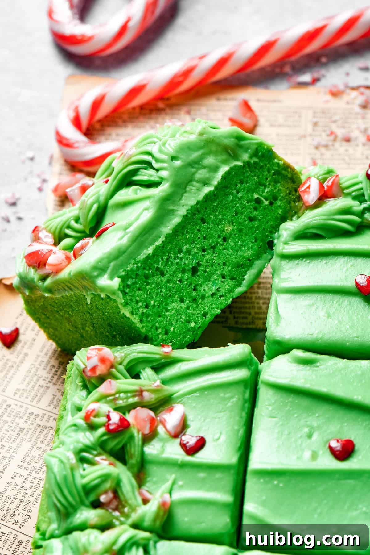 A slice of vibrant green Grinch cake turned on its side, revealing its moist texture.