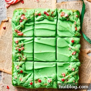 A Grinch cake is cut into 12 pieces, showcasing its green layers and festive frosting.