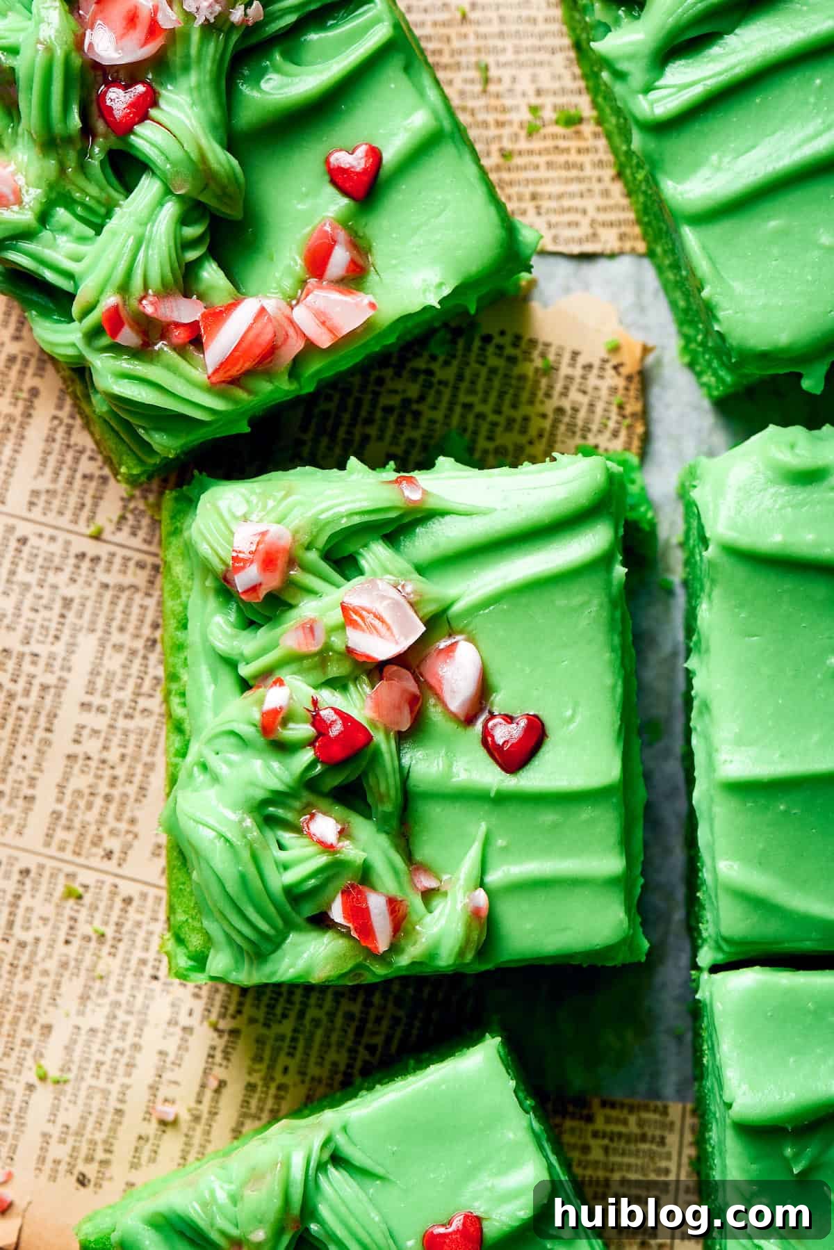 Crushed candy and red heart sprinkles adorn slices of bright green Grinch cake.