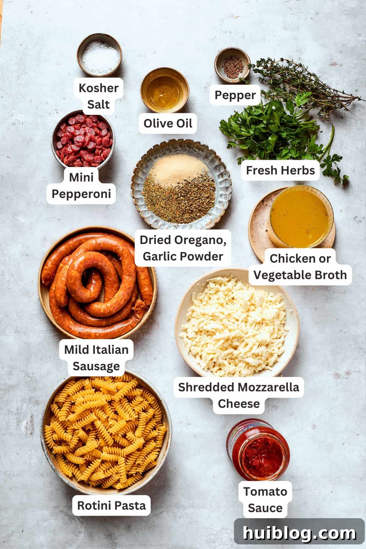Ingredients for a savory pizza pasta dish are meticulously portioned and clearly labeled on a countertop.