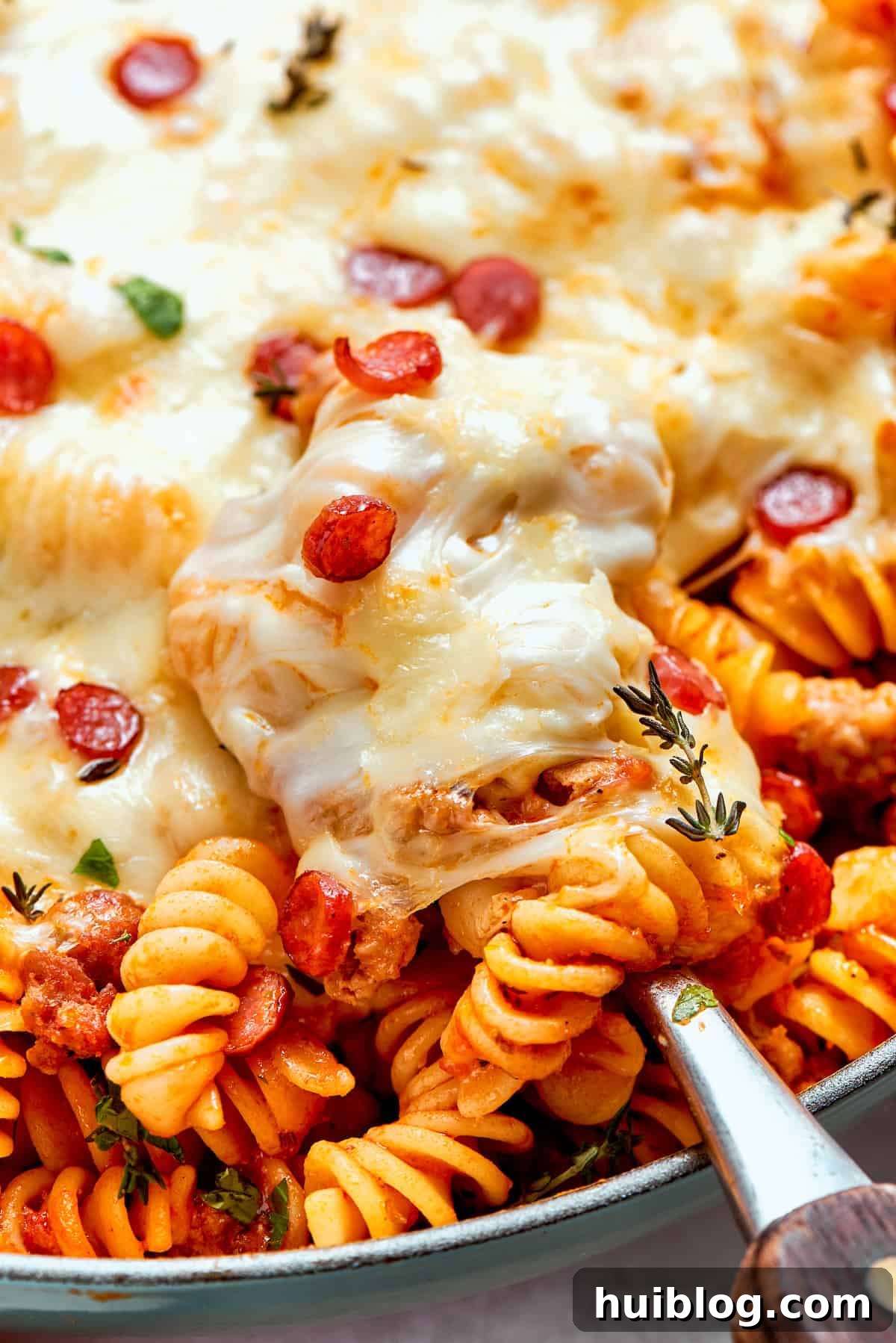 Close-up of bubbling, melted mozzarella cheese on top of a pan of pizza pasta.