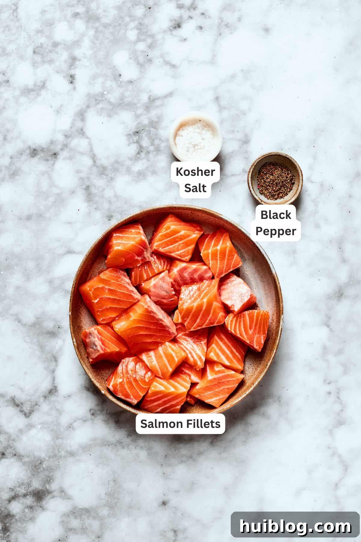 Cubed salmon fillets seasoned with salt and freshly ground black pepper, prepared for cooking.