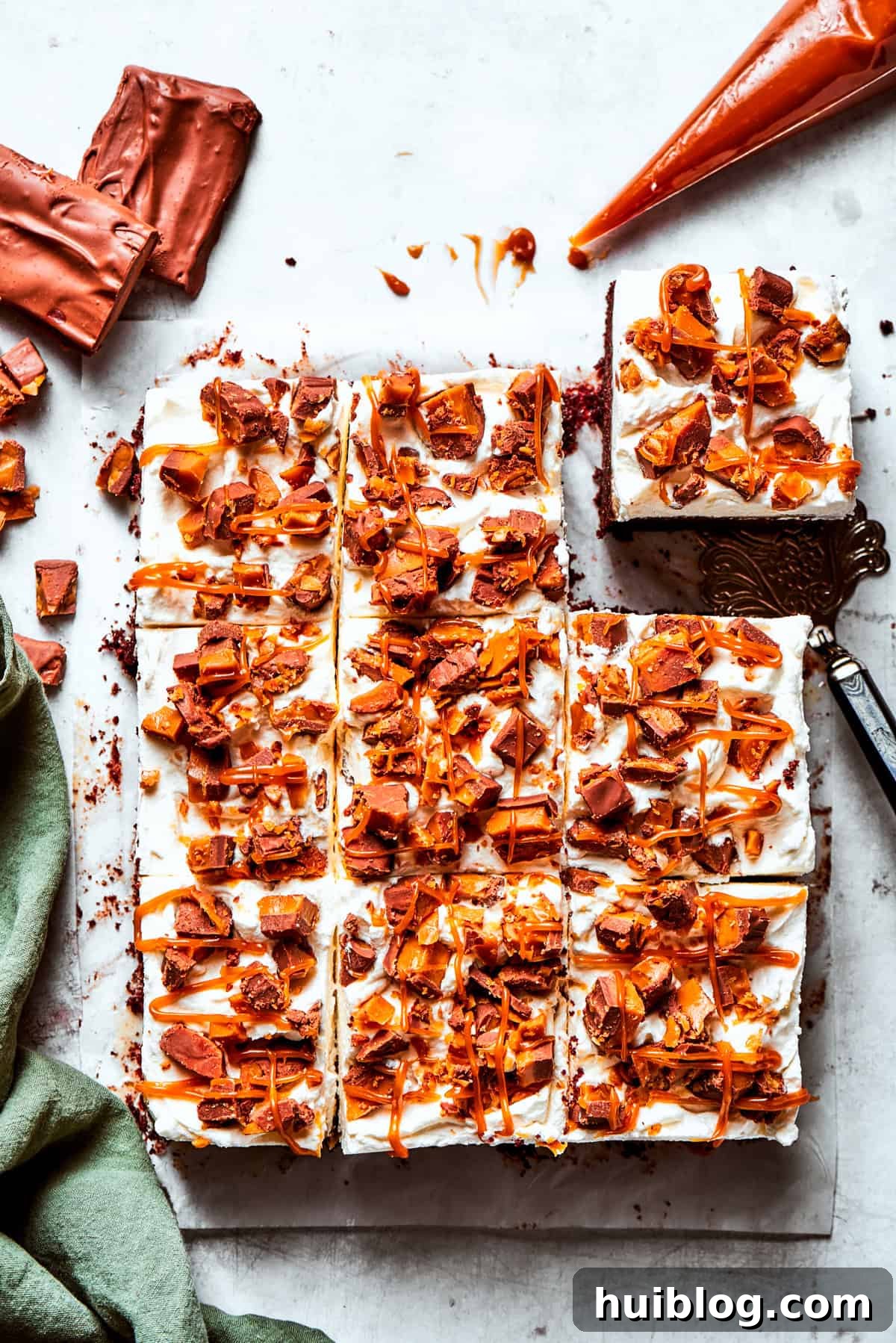 Squares of better than sex cake, drizzled with caramel and topped with whipped cream and candy pieces.