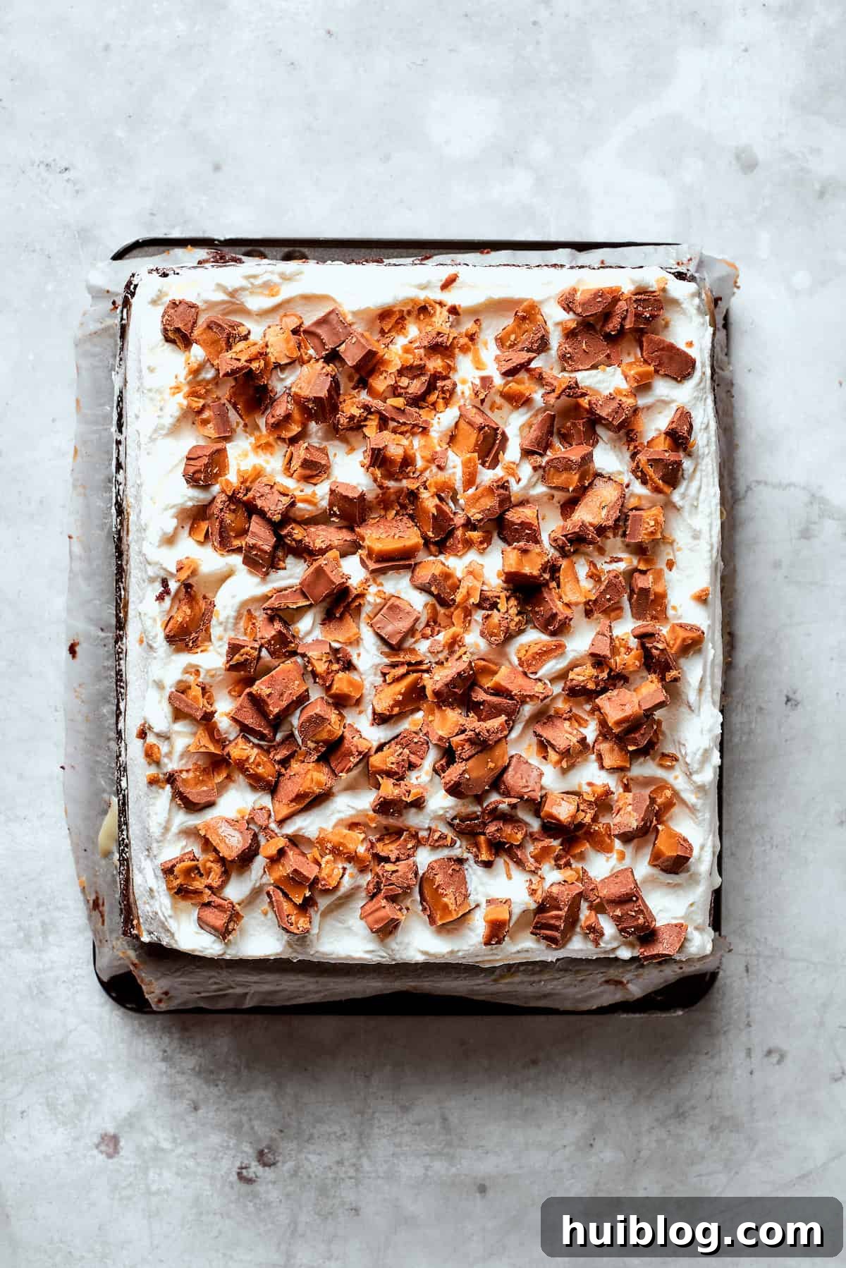 Finely chopped candy bars sprinkled over the top of a Better Than Sex Cake with whipped cream.
