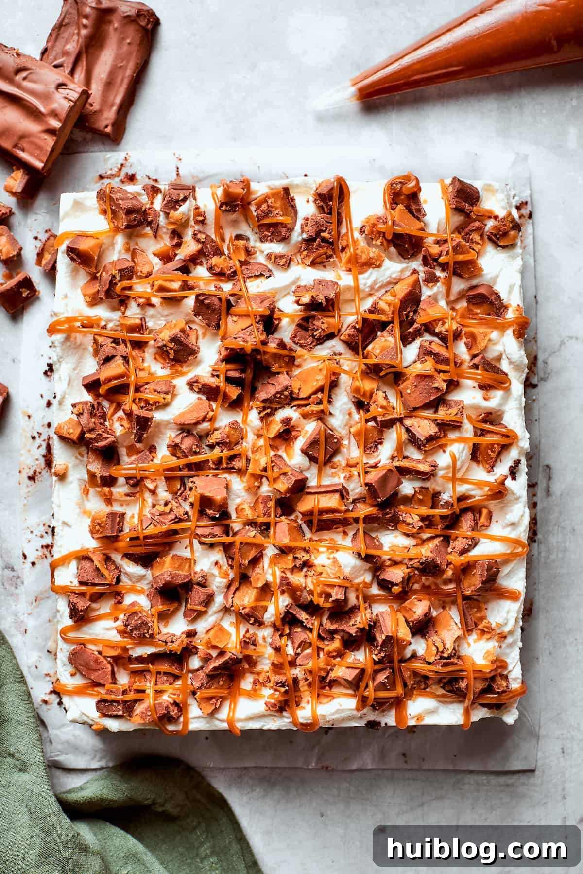A finished Better Than Sex Cake, topped with whipped cream, chopped candy bars, and a final caramel drizzle.