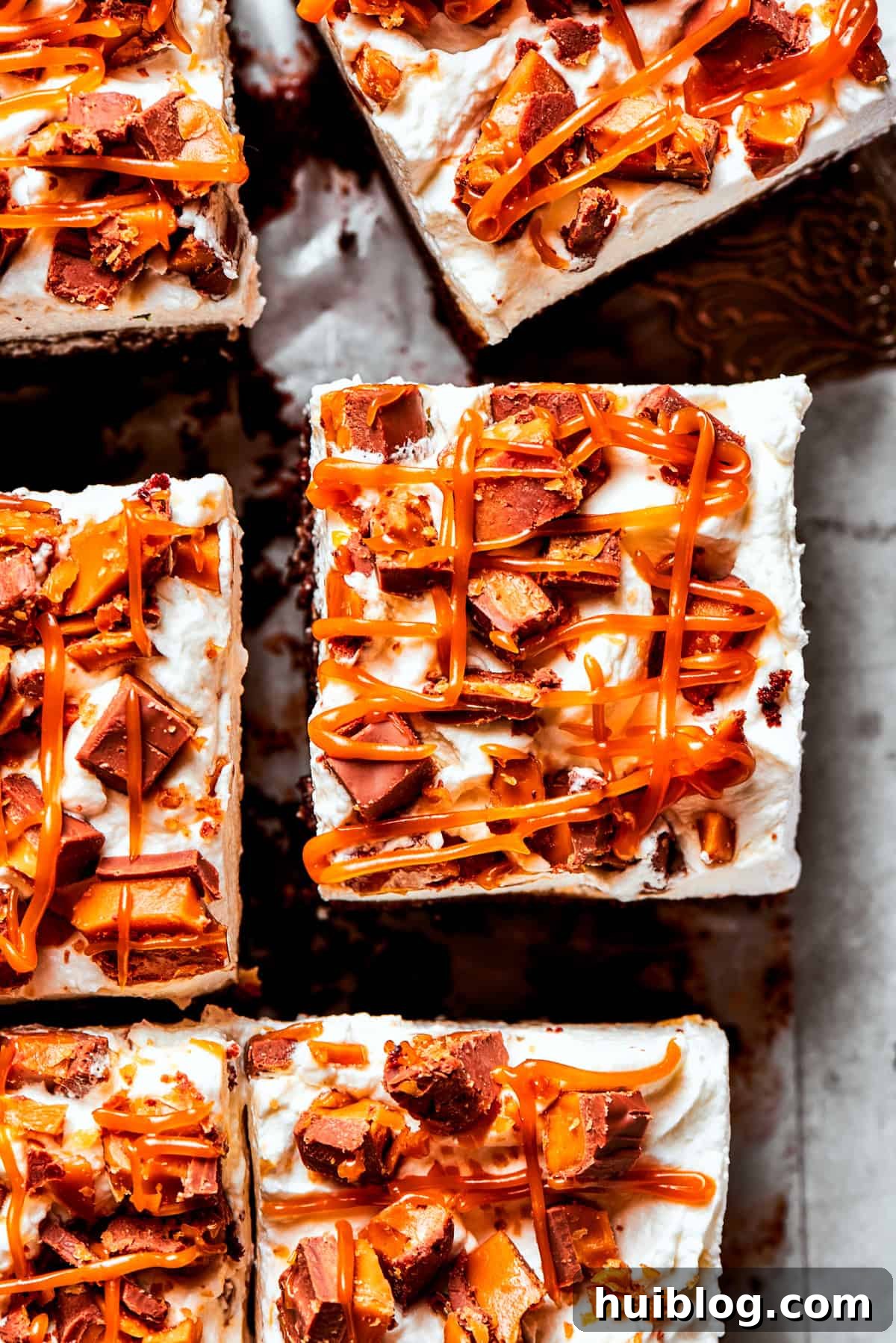 Close-up of a slice of better than sex cake, showing distinct layers of cake, sauce, whipped cream, and candy topping.