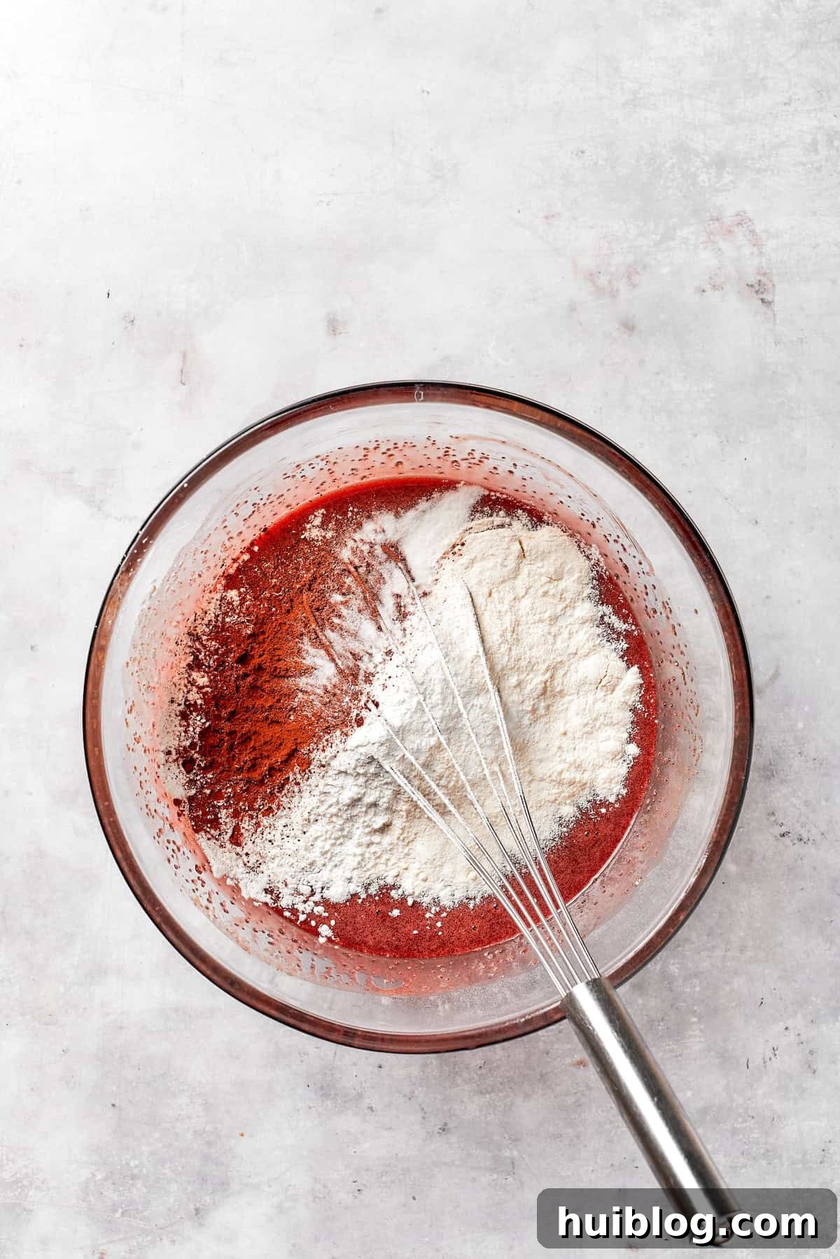 Flour is whisked into red velvet brownie batter.
