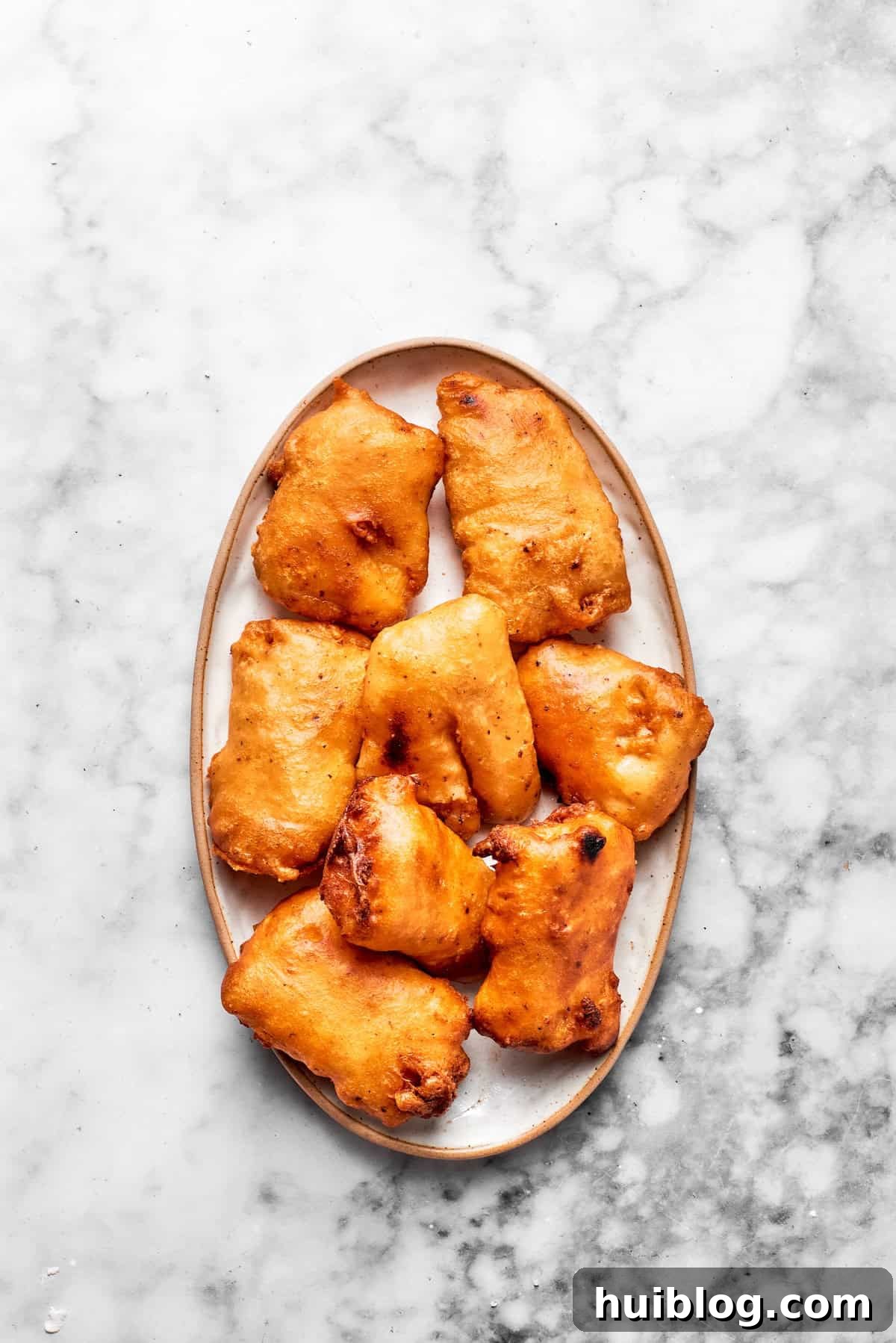 This crispy, crunchy fish sandwich is served on toasty sweet rolls with lemony tartar sauce and a squeeze of lime! It's quick and easy to make! Golden-brown, crispy fried fish fillets are neatly arranged on a plate, ready to be assembled into delicious sandwiches.