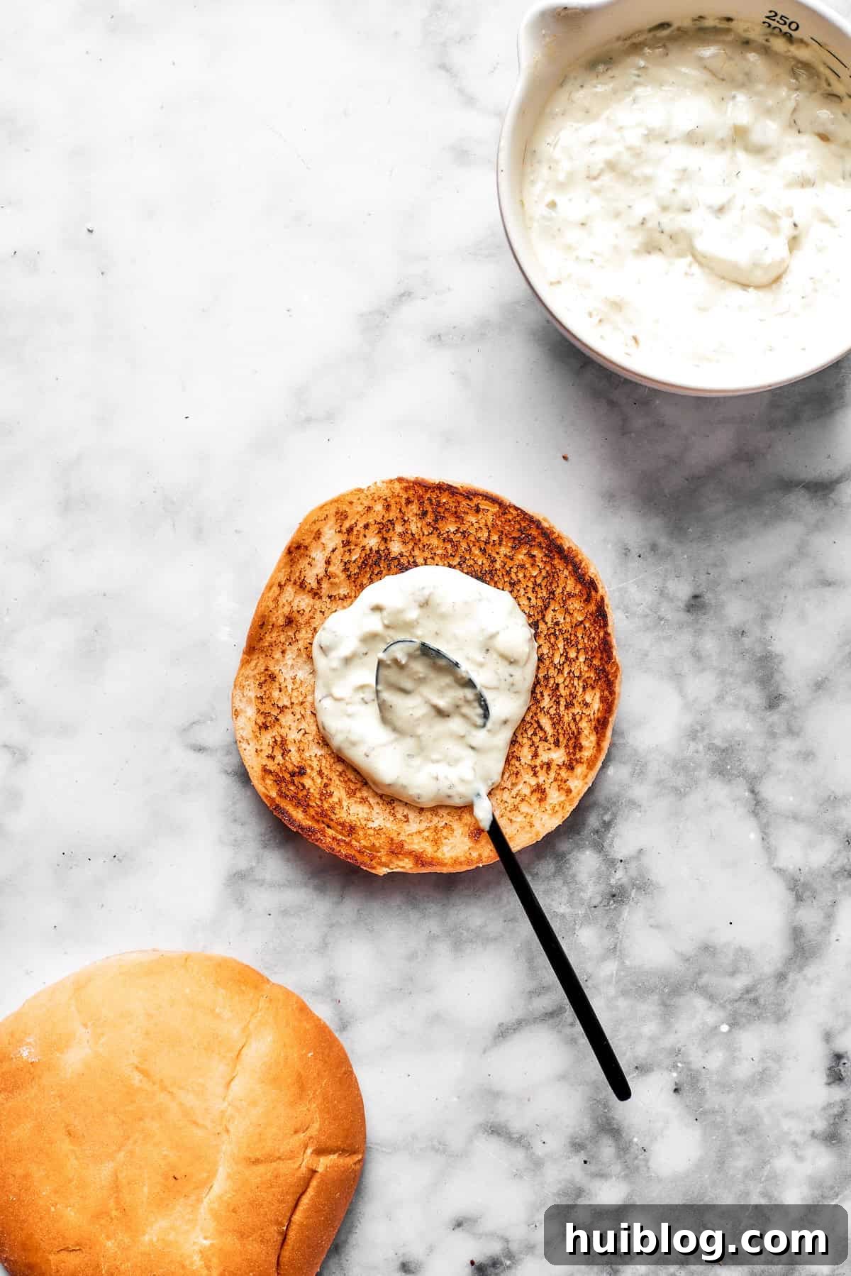 This crispy, crunchy fish sandwich is served on toasty sweet rolls with lemony tartar sauce and a squeeze of lime! It's quick and easy to make! Creamy tartar sauce is generously spread on the bottom half of a golden-toasted brioche bun, preparing it for the crispy fish fillet.