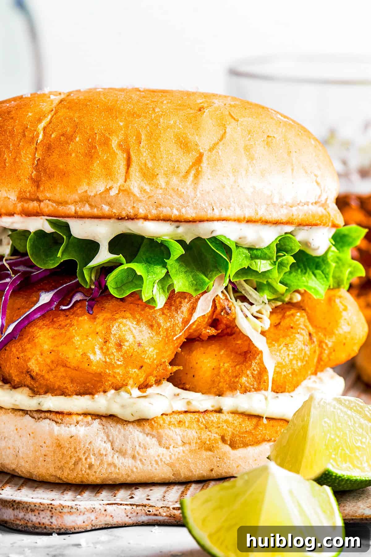 This crispy, crunchy fish sandwich is served on toasty sweet rolls with lemony tartar sauce and a squeeze of lime! It's quick and easy to make! A freshly prepared, crispy fish sandwich, garnished with a vibrant lime wedge, ready to be enjoyed.