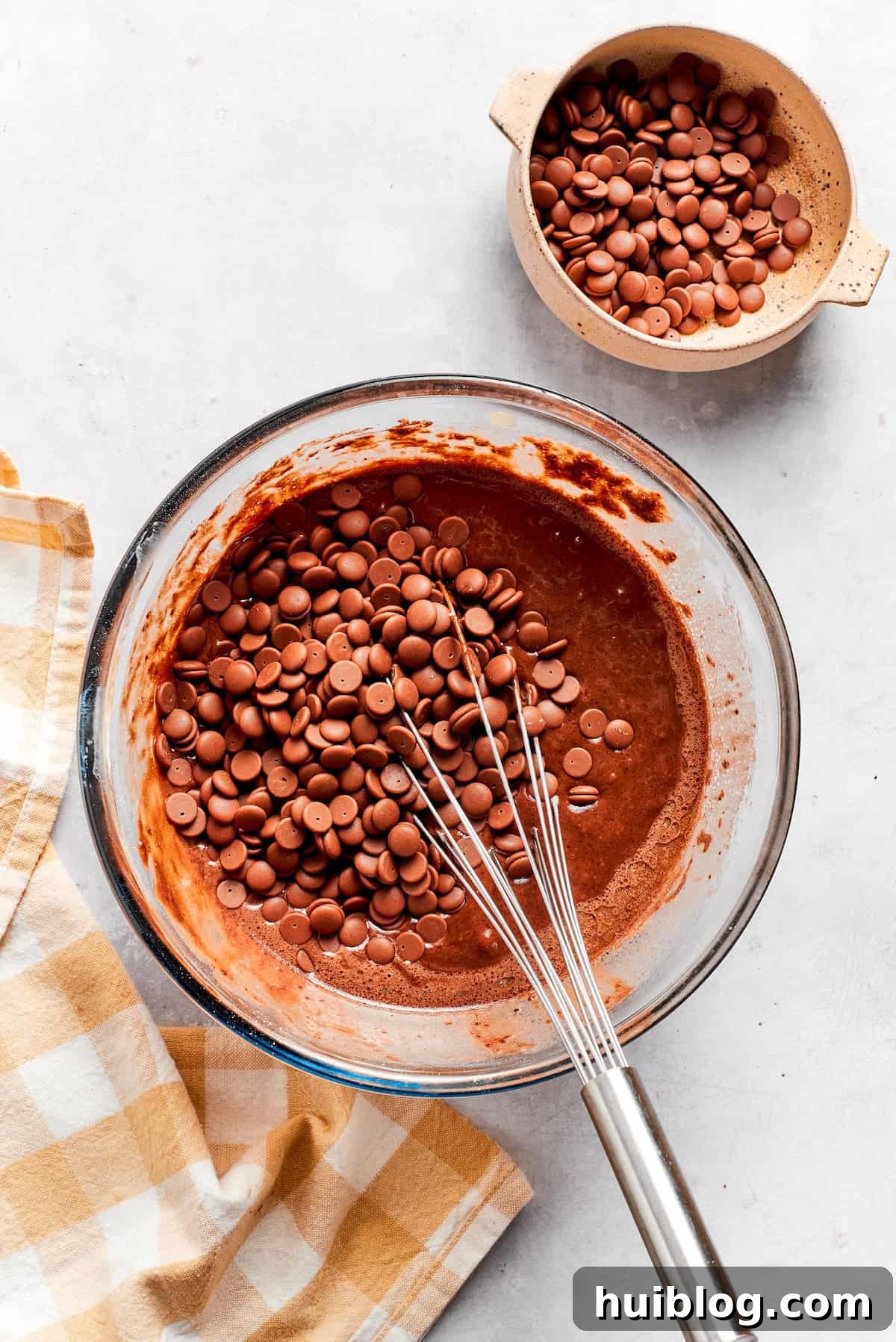 Chocolate chips being folded into the smooth chocolate muffin batter.