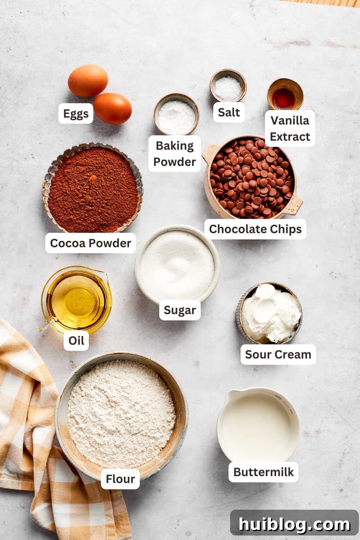 Labeled ingredients for baking chocolate muffins laid out on a kitchen surface.