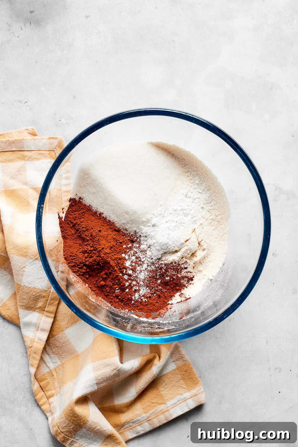 Dry ingredients for chocolate muffins are meticulously mixed in a bowl.