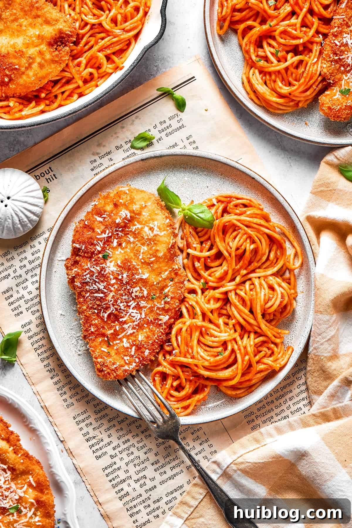 Three elegantly plated servings of Crusted Chicken Romano, each with a golden chicken cutlet atop marinara-coated spaghetti.