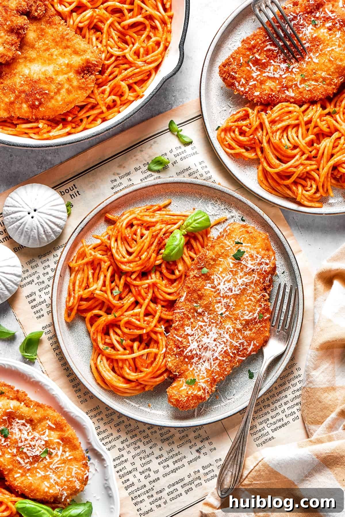 Two beautifully presented plates of Crusted Chicken Romano, each featuring a golden chicken cutlet nestled atop a generous portion of spaghetti and marinara.