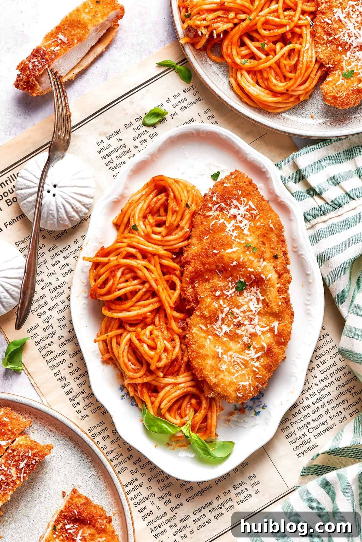 An inviting platter showcasing several pieces of golden Crusted Chicken Romano alongside a bountiful serving of spaghetti coated in rich marinara sauce, ready to be enjoyed.
