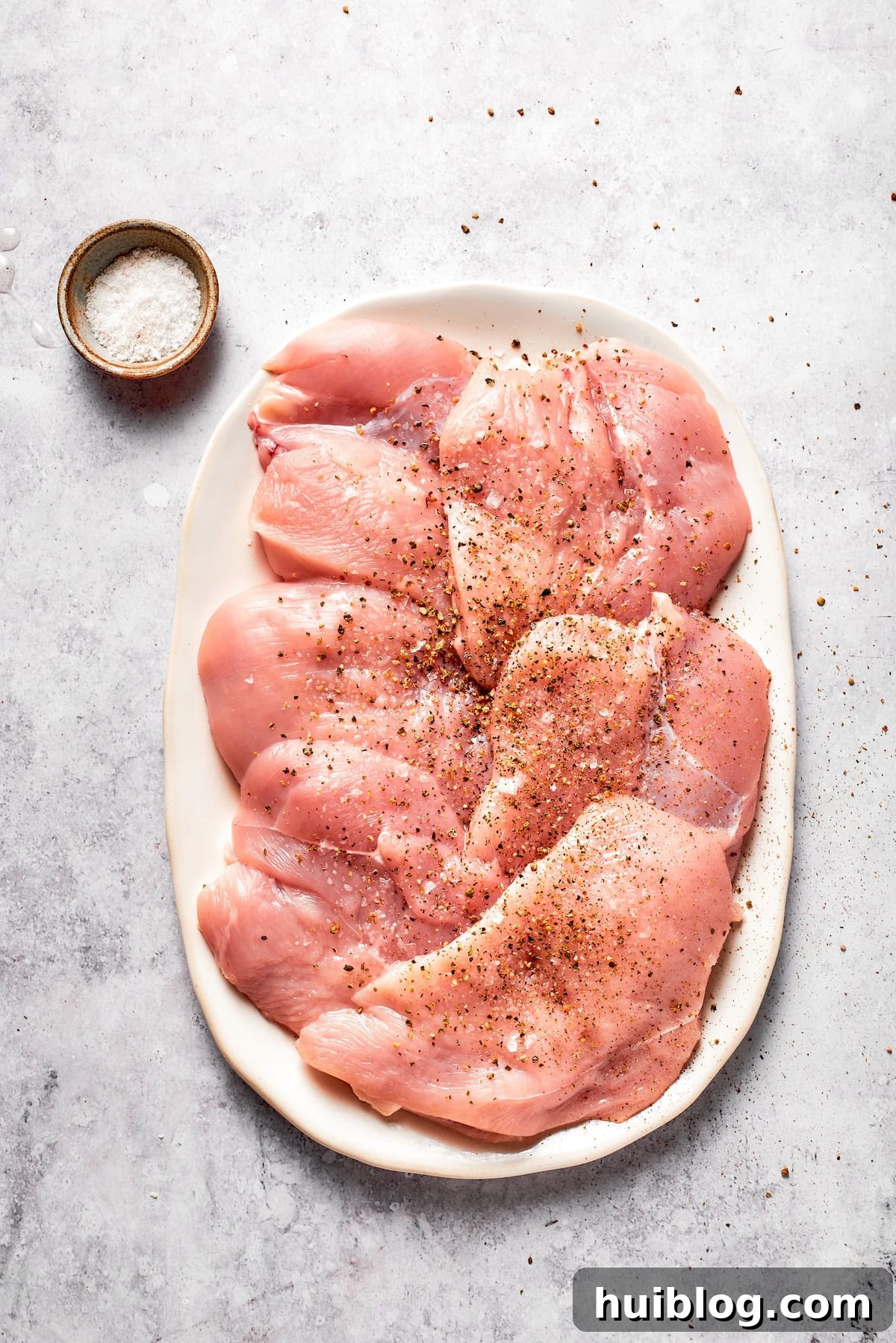 Chicken breasts, pounded to an even thickness and lightly seasoned with salt and pepper, ready for breading.