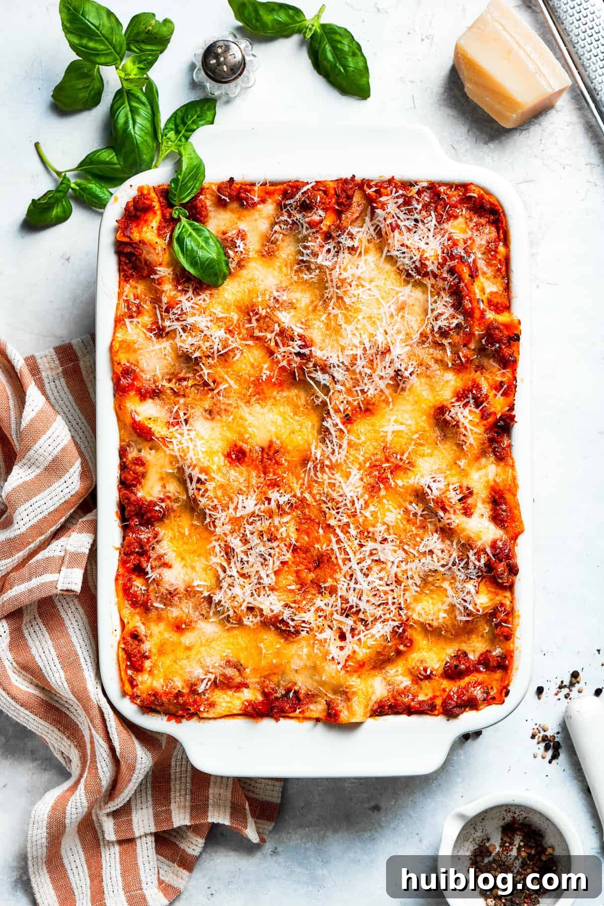 An overhead view of a perfectly baked, golden-brown beef lasagna in a white baking dish, fresh from the oven and resting.