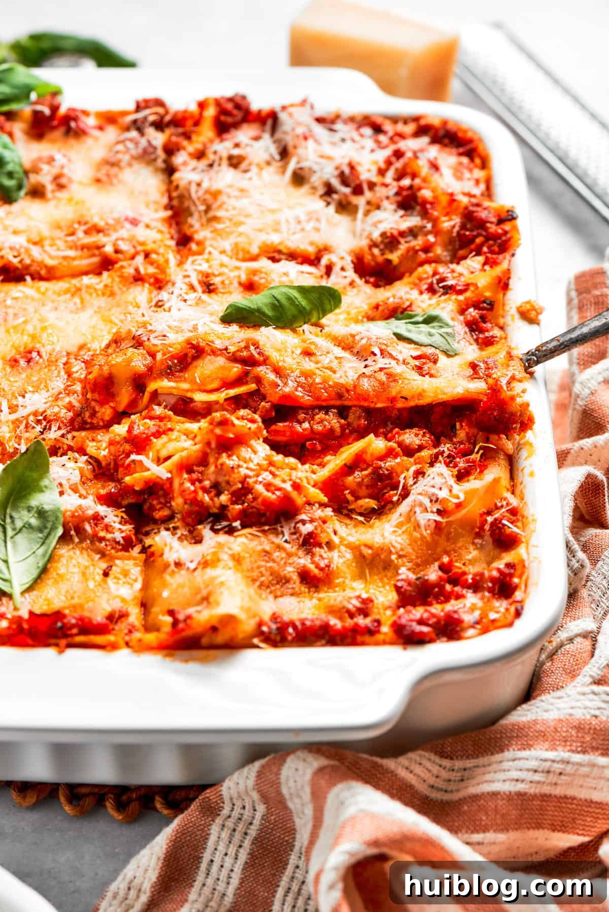A spatula gently lifts a perfectly baked slice of beef lasagna from the baking dish, revealing its distinct layers.