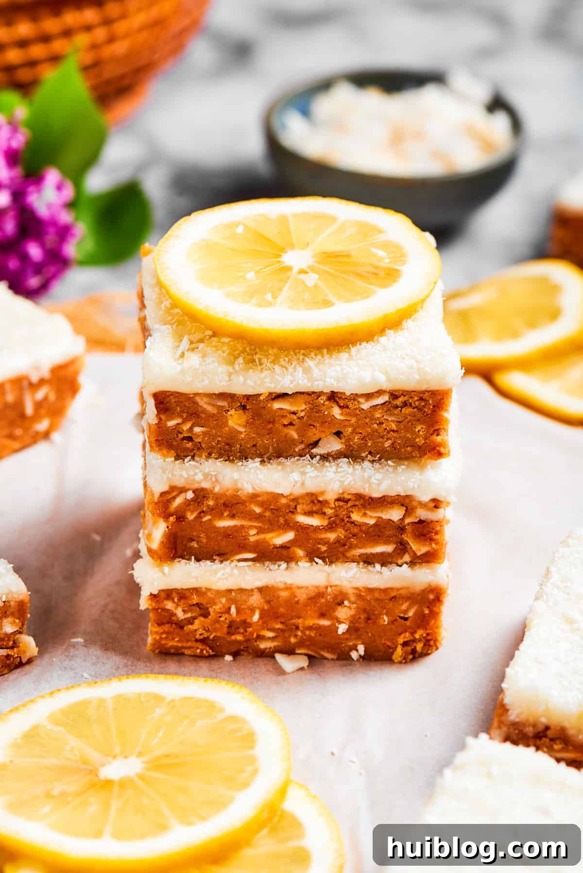 A beautifully stacked presentation of lemon slice squares, garnished with a fresh lemon wedge.