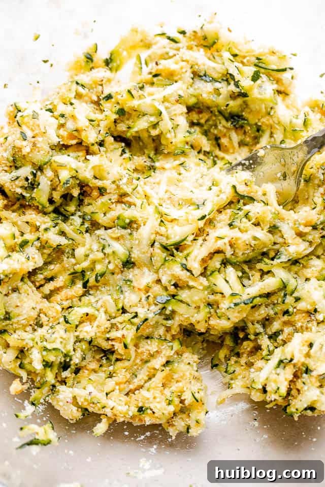 Golden Zucchini Fritters 3 Freshly shredded zucchini in a clear glass bowl, ready for preparation.