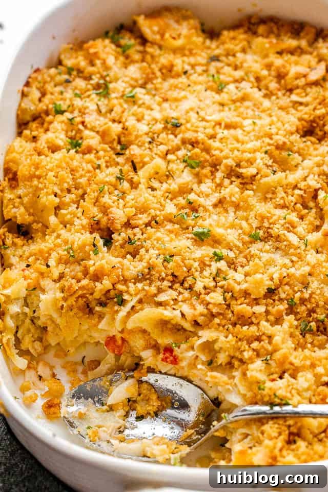 This Tuna Noodle Casserole is a creamy, cheesy, and comforting dish made from scratch, perfect for an easy and satisfying weeknight dinner. top side shot of a serving spoon inside a baking dish with tuna noodle casserole