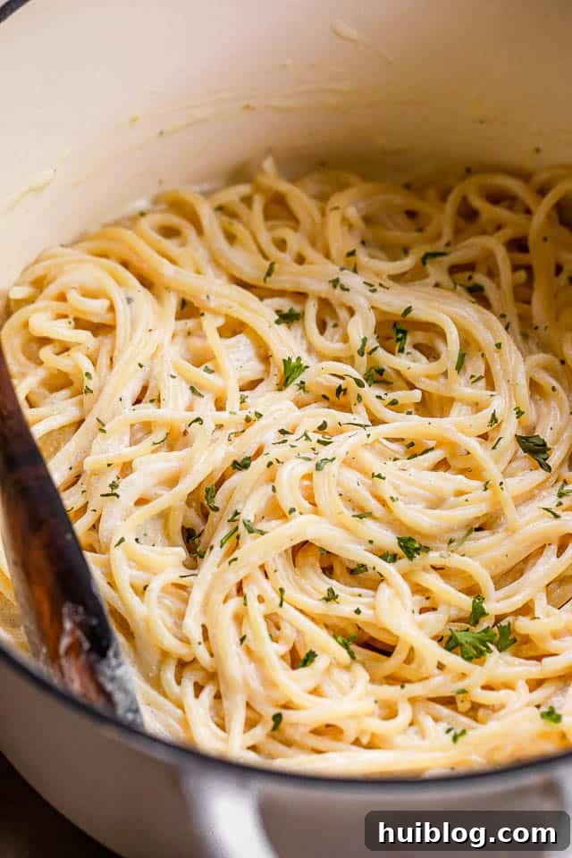 cooked spaghetti in a white dutch oven with sauce mixed in