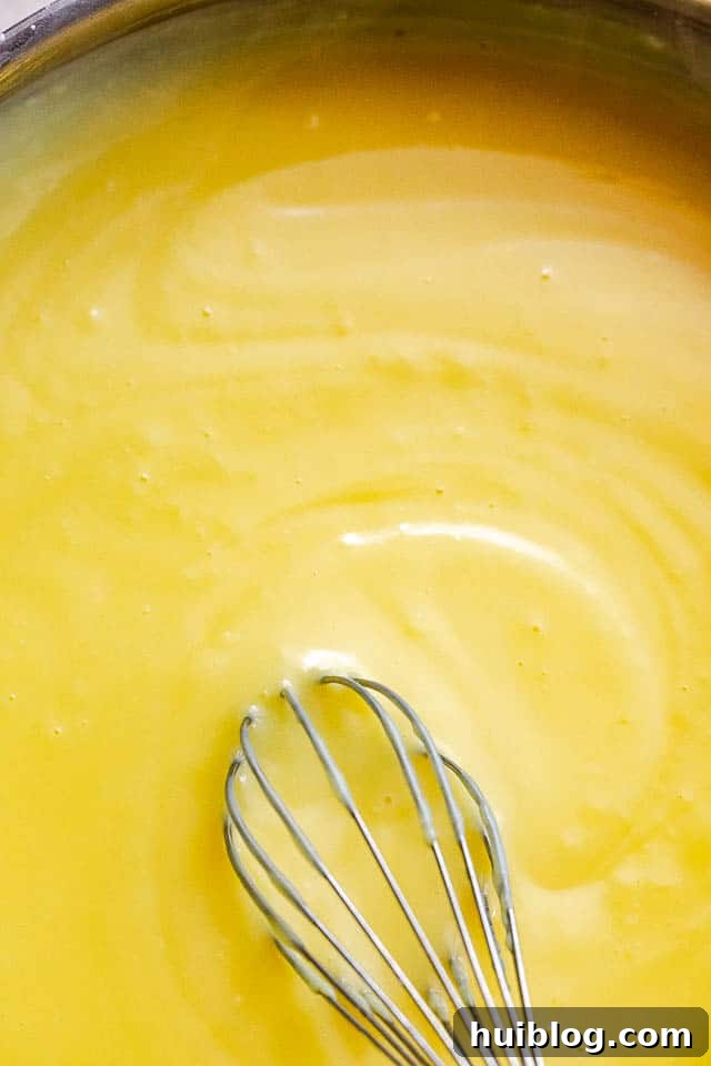 Velvet Banana Pudding Delight 3 whisking homemade vanilla pudding in a saucepan on the stovetop, showing the creamy texture developing
