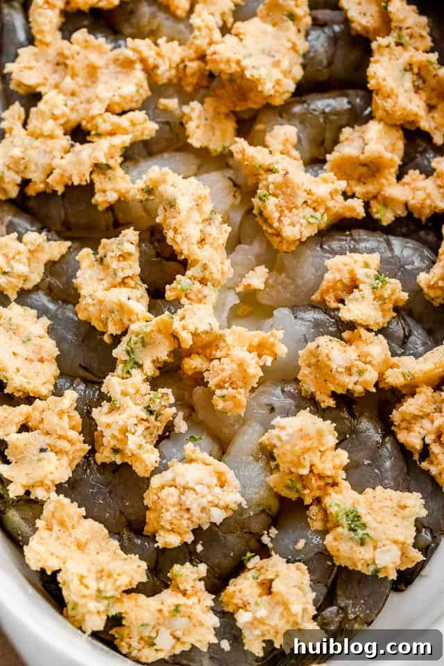 Shrimp Delectables: Garlic Butter Baked and De Jonghe 4 top view of raw shrimp with dollops of butter on top of them.