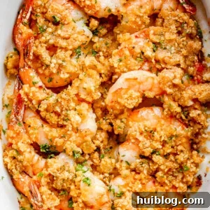overhead shot of arranged shrimp in a white oval dish and topped with garlic butter and breadcrumbs mixture