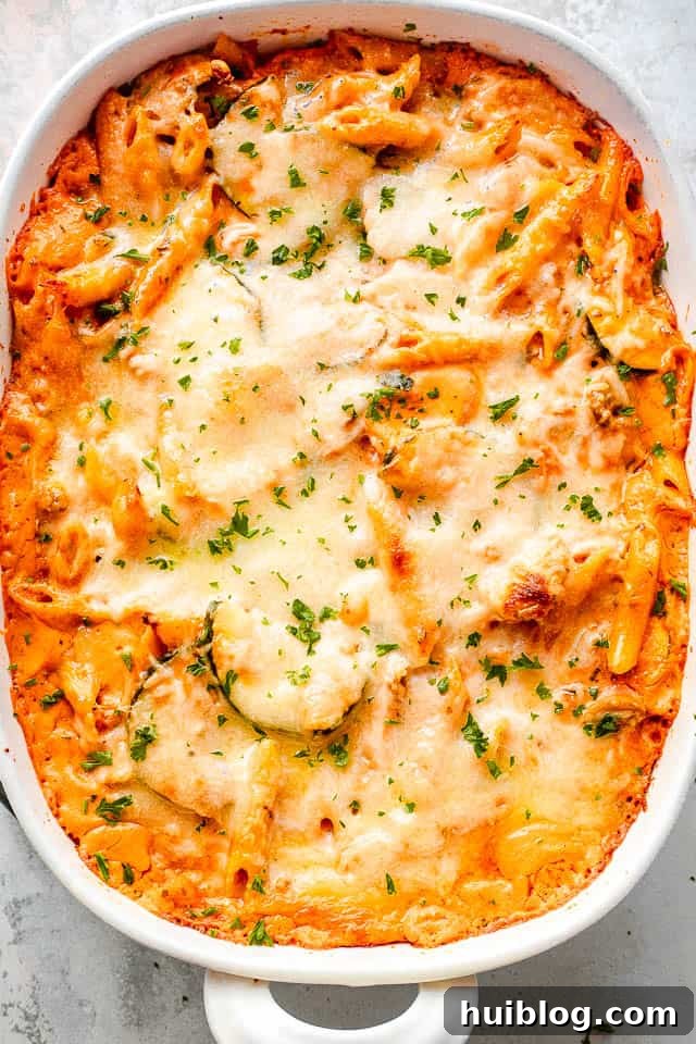 Velvety Zucchini Mushroom Pasta Bake 2 An overhead shot of a golden-brown, cheesy baked pasta and zucchini casserole, ready to be served from a rectangular baking dish.