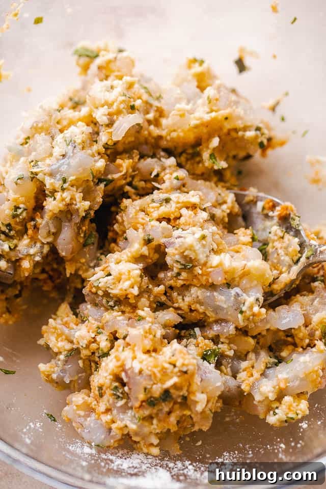 Golden Coconut Shrimp Patties 4 A close-up of the raw mixture for coconut shrimp cakes in a mixing bowl before being formed.