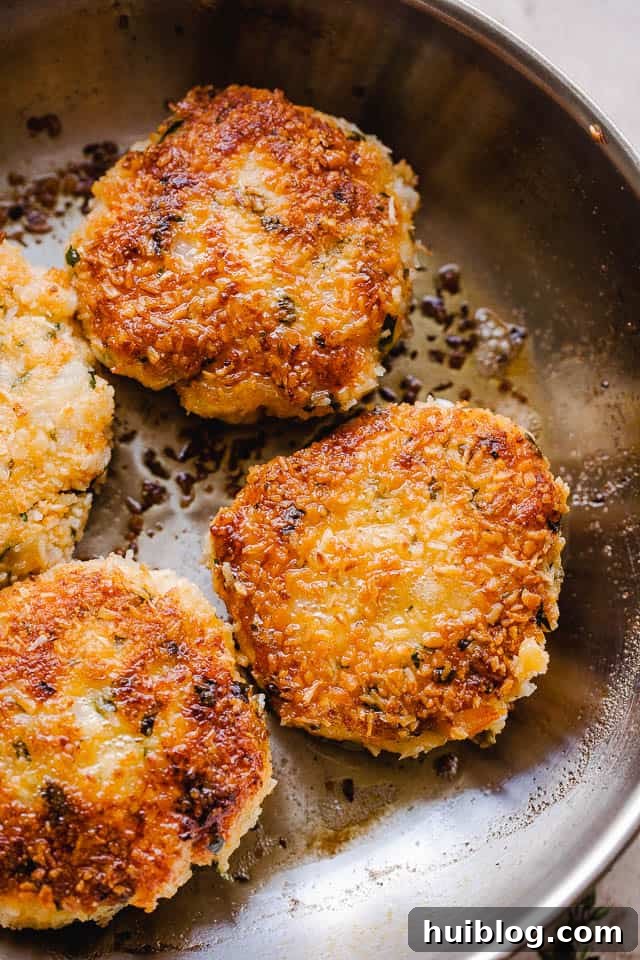 Golden Coconut Shrimp Patties 5 Coconut shrimp cakes sizzling and cooking in a large skillet filled with hot oil.