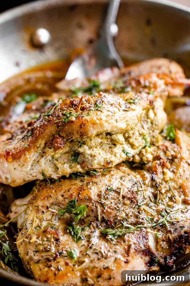 close-up side view of a perfectly cooked pesto and feta stuffed pork chop on a white plate, showcasing the delicious filling