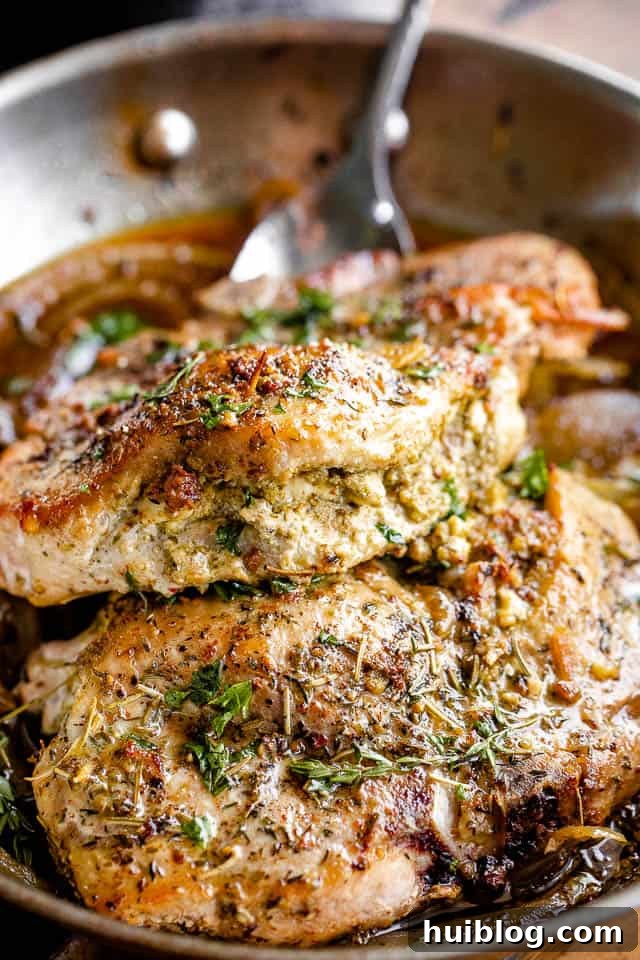side shot of a single pesto and feta stuffed pork chop on a wooden board, highlighting the rich filling