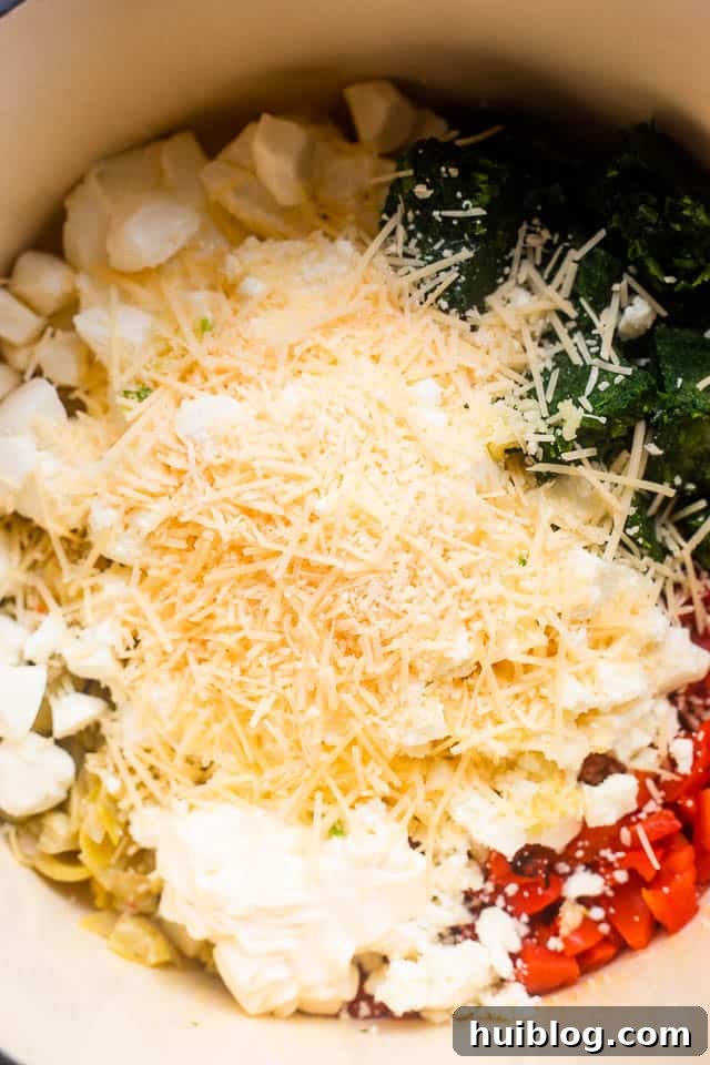 Overhead shot of all ingredients for spinach artichoke dip layered in a slow cooker before cooking