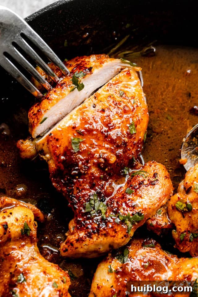 Sticky Apple Cider Chicken Thighs 3 A close-up shot of a knife slicing into a piece of apple cider glazed chicken thigh, revealing its tender, juicy interior.