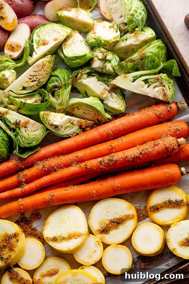 Raw carrots, brussels sprouts, yellow squash, and fingerling potatoes, prepped and arranged on a baking sheet, ready for the balsamic vinaigrette and roasting.