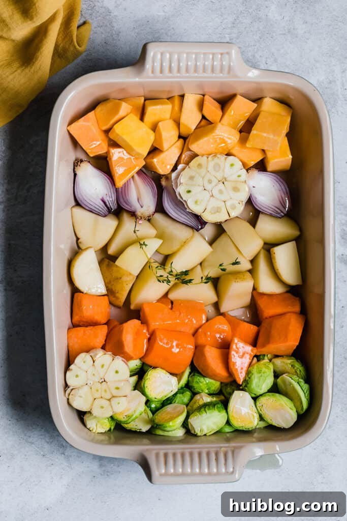 Chopped root vegetables in a roasting pan with oil and thyme.