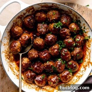White skillet filled with bacon bourbon meatballs and topped with fresh parsley.