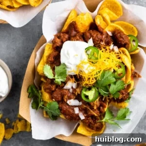 Boats of Frito pie served with sour cream, grated cheese, diced onion and slices of jalapeño.