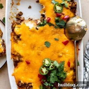 Baking dish with John Wayne Casserole with a portion served and a golden spoon on the side.