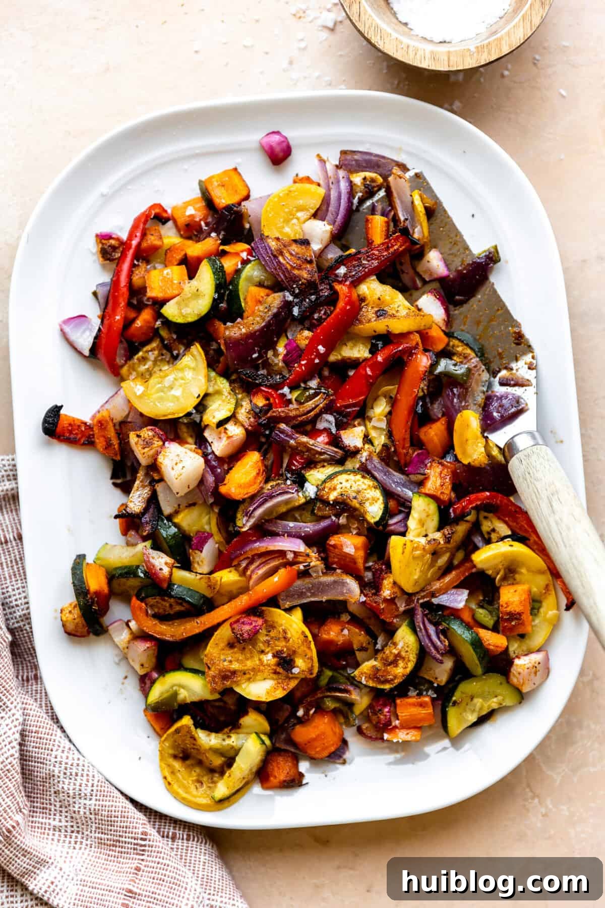 White plate filled with roasted mexican vegetables with a spatula for serving.