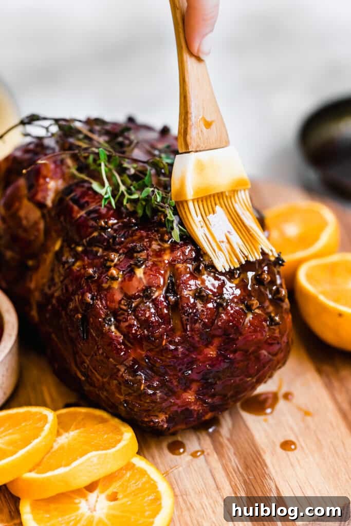 Topping the Cooked Christmas Ham with the Rest of the Glaze, ensuring every inch is coated.