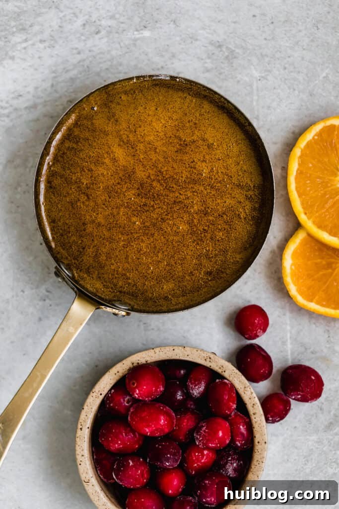 A Pan Filled with Homemade Brown Sugar Glaze Beside a Bowl of Fresh Fruit, ready to be applied.